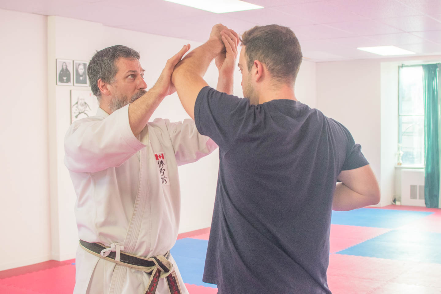 Shihan Beardwood teaching a new karate student details on how to execute a high block.